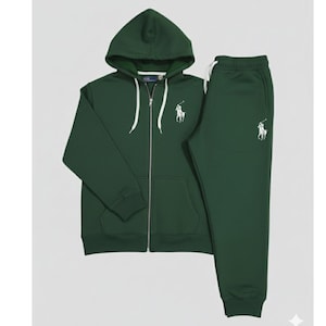 May include: A dark green tracksuit set featuring a hooded zip-up jacket and matching sweatpants. The jacket has a white drawstring and a white embroidered logo on the chest. The sweatpants also have the same logo. The set is made of a soft material.