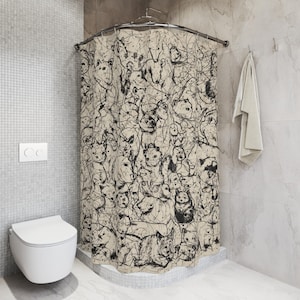 May include: Shower curtain with a beige background and a black abstract pattern of various animal faces. The curtain is hanging in a bathroom with a white toilet and a towel.