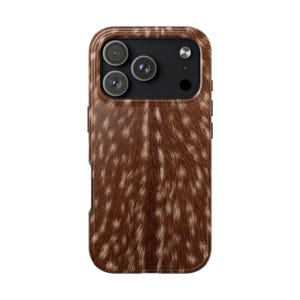 Op de afbeelding: Een smartphonehoesje met een bruin en wit gevlekt vachtpatroon. De achterkant van het hoesje heeft een rechthoekige uitsparing linksboven voor een drievoudig camerasysteem, inclusief drie ronde lenzen en een kleine ronde flitser.