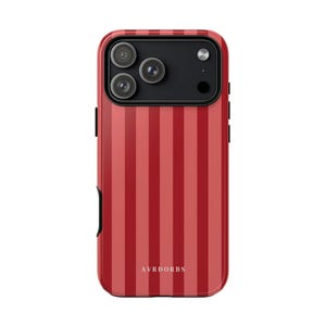 May include: A red and dark red vertically striped phone case featuring a black rectangular camera module with three circular lenses and a flash. The word AVRDORBS is printed in small white capital letters near the bottom of the case.
