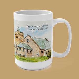 May include: A white ceramic mug featuring a watercolor illustration of the Presbyterian Church Webb Chapel 1887. The artwork depicts a stone building with a green roof, a tall steeple, and a cross, set against a light blue sky and green grass.