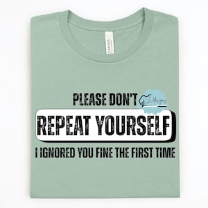 May include: A light green t-shirt with the text "PLEASE DON'T REPEAT YOURSELF I IGNORED YOU FINE THE FIRST TIME" in black. The words "REPEAT YOURSELF" are in a white box with a black border.