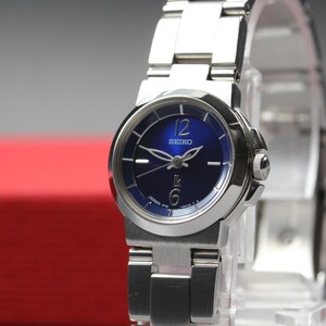 Op de afbeelding: Een Seiko roestvrijstalen polshorloge met een blauwe wijzerplaat. Het horloge heeft zilveren wijzers en uurmarkeringen, met de nummers 12 en 6 zichtbaar. Het horloge heeft een zilveren band.