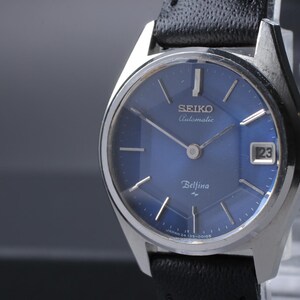 Puede incluir: Reloj Seiko Bell-Matic vintage con esfera azul y agujas plateadas. El reloj tiene una pantalla de fecha a las 3 en punto y una correa de cuero negro. La esfera del reloj mide aproximadamente 2,5 cm de diámetro.