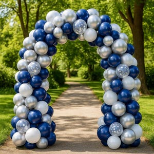 May include: A large archway constructed from numerous balloons in shades of navy blue, silver, and white. The arrangement includes solid-colored balloons alongside several clear balloons filled with small white confetti dots, forming a curved structure.