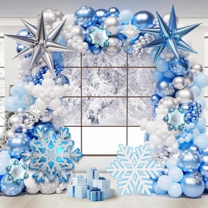 May include: A balloon arch featuring a mix of blue, silver, and white balloons in various sizes. The arrangement includes large silver and blue star-shaped foil balloons, snowflake-shaped foil balloons, and small gift boxes at the base.