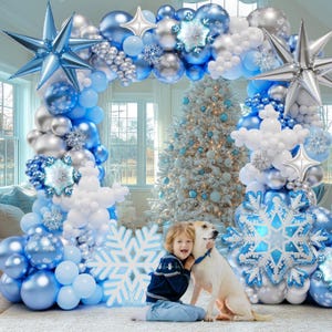 May include: A large balloon arch featuring blue, silver, and white balloons in various sizes, accented with large foil star balloons, snowflake-shaped foil balloons, and smaller snowflake cutouts, creating a festive winter-themed display.