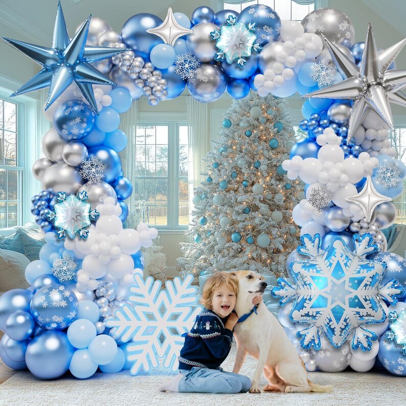 May include: A large balloon arch featuring blue, silver, and white balloons in various sizes, accented with large foil star balloons, snowflake-shaped foil balloons, and smaller snowflake cutouts, creating a festive winter-themed display.