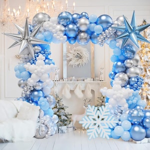 May include: A balloon arch kit featuring a mix of metallic blue, silver, and matte white balloons. The display includes large silver and blue star-shaped foil balloons, white snowflake-shaped balloon clusters, and a large white snowflake cutout.