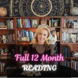 May include: A woman smiles, holding tarot cards in front of a bookshelf filled with books. The text "Full 12 Month READING" is displayed in pink and white. A crystal ball and more tarot cards are on the table.