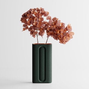 Pode incluir: Um vaso retangular verde escuro com um design curvo e rebaixado, segurando flores secas laranja-castanhas. O vaso tem uma superfície texturizada e um interior contrastante. Decoração de casa.