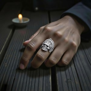 Peut inclure: Bague en argent représentant un crâne orné d'une coiffe élaborée. La bague présente des gravures détaillées d'un crâne avec une coiffe d'inspiration amérindienne. La bague est portée sur un doigt, mettant en valeur son savoir-faire complexe et son esthétique audacieuse.