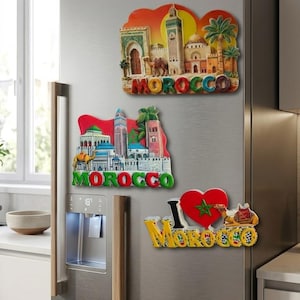 May include: Three decorative refrigerator magnets featuring Moroccan themes. The top magnet shows a mosque and camel with the text MOROCCO. The middle magnet depicts city architecture and a camel with the text MOROCCO. The bottom magnet says I love MOROCCO.