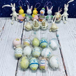 May include: A collection of Easter-themed ornaments, including bunny and chick figurines, and decorative eggs. The ornaments feature pastel colors, ribbons, and intricate designs, perfect for spring decor.