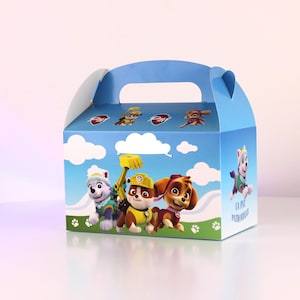 May include: A blue party favor box featuring characters from the Paw Patrol animated series. The box has a handle and is decorated with images of the cartoon dogs, clouds, and paw prints. The box is designed for children's parties.