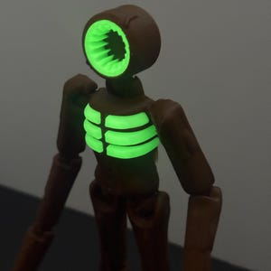 May include: A brown Siren Head action figure with a glowing green head and chest. The figure has articulated joints and a detailed design, perfect for collectors or fans of the horror genre.