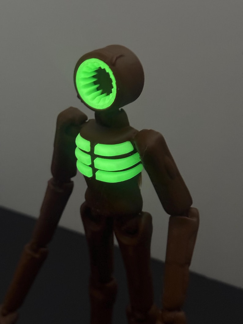 May include: A brown Siren Head action figure with a glowing green head and chest. The figure has articulated joints and a detailed design, perfect for collectors or fans of the horror genre.