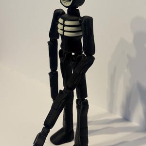 May include: A black articulated figure with a siren-shaped head and a ribcage design. The figure's head has a white, ribbed interior. The figure's limbs are jointed, allowing for various poses. The figure is standing on a white surface.