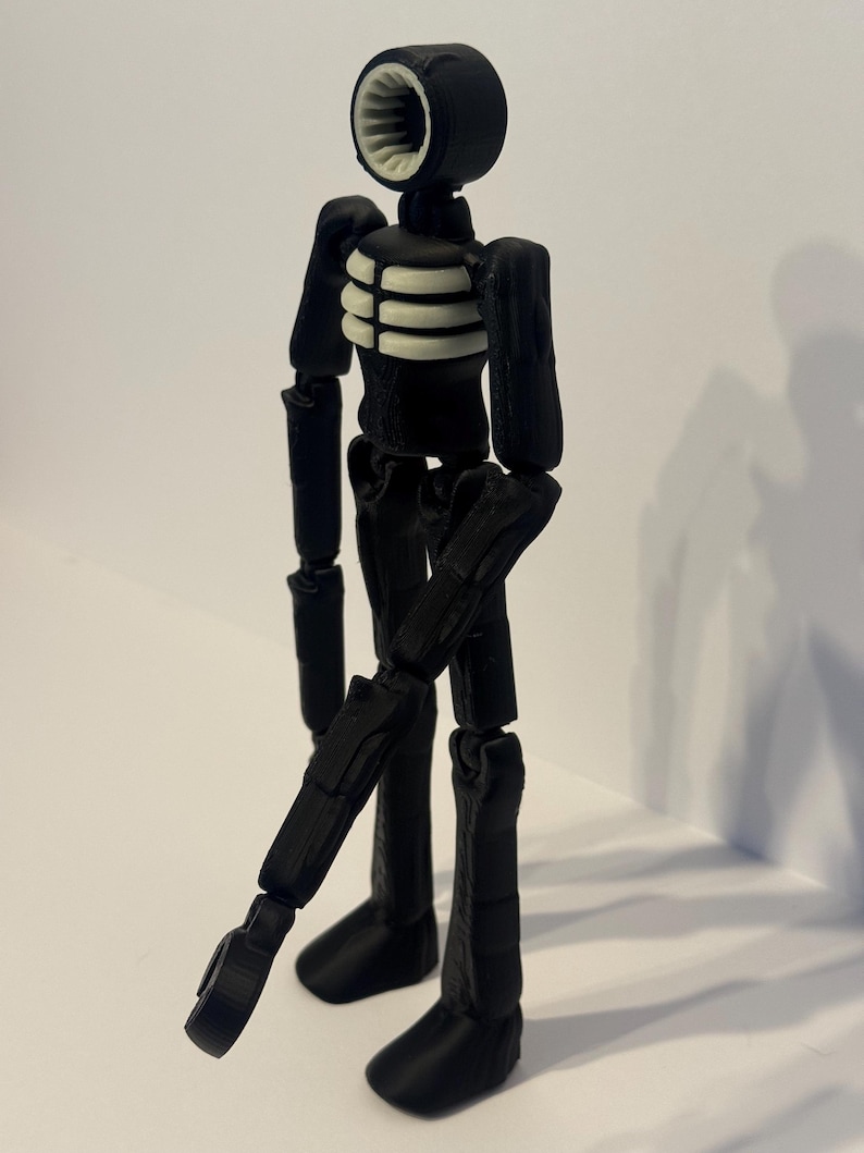 May include: A black articulated figure with a siren-shaped head and a ribcage design. The figure's head has a white, ribbed interior. The figure's limbs are jointed, allowing for various poses. The figure is standing on a white surface.