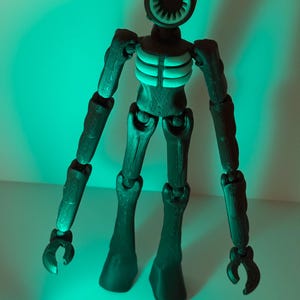 May include: A dark green articulated figure with a circular head featuring a speaker-like design. The figure has a ribcage detail and claw-like hands. The figure is standing in front of a green background.