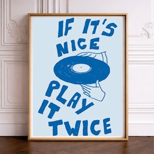 Könnte beinhalten: Gerahmter Kunstdruck mit hellblauem Hintergrund und Holzrahmen. Der Druck zeigt eine blaue Schallplatte, die von Händen gehalten wird, mit dem Text "IF IT'S NICE PLAY IT TWICE" in blauen Blockbuchstaben.