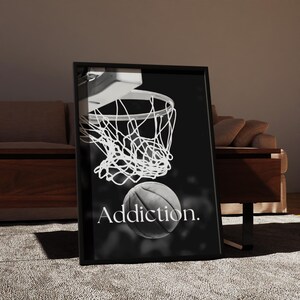 May include: Black and white framed print featuring a basketball net and ball. The word "Addiction" is printed below the ball. The image is set against a dark background.