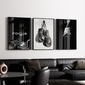 May include: A set of three framed monochrome art prints. One shows the word "FOCUS" above a gym scene. The central print features hanging boxing gloves. The third print depicts a hand wrapped in boxing tape.