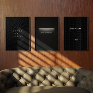 May include: Three framed motivational posters hang on a wood-paneled wall above a tufted sofa. The posters feature black backgrounds with white text that reads "Purpose Fuels Passion", "now or never", and "DISCIPLINE".