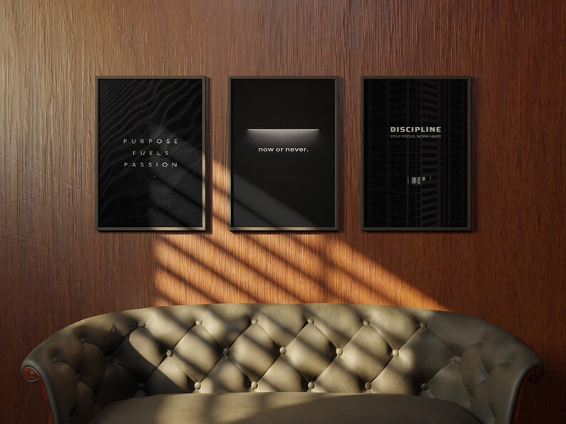 May include: Three framed motivational posters hang on a wood-paneled wall above a tufted sofa. The posters feature black backgrounds with white text that reads "Purpose Fuels Passion", "now or never", and "DISCIPLINE".