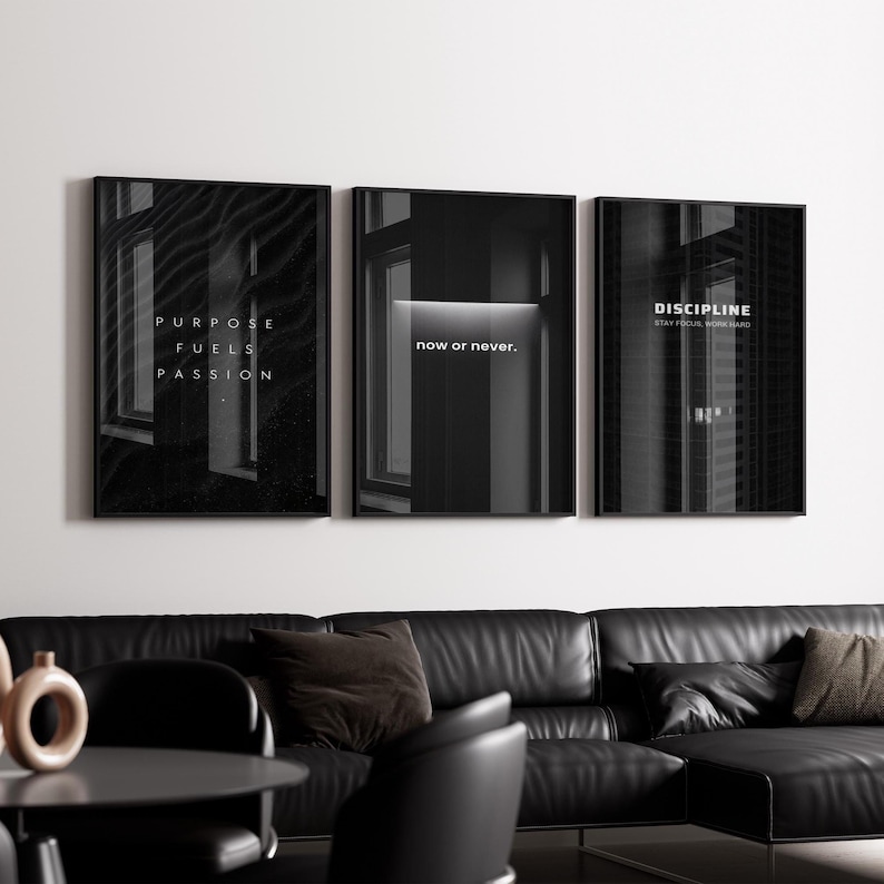May include: Three framed black and white art prints with motivational quotes. The first print reads "PURPOSE FUELS PASSION", the second says "now or never.", and the third says "DISCIPLINE STAY FOCUSED WORK HARD". The prints are displayed above a black leather sofa.