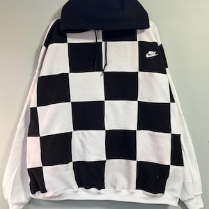 Op de afbeelding: Zwart-wit geblokte Nike hoodie met een zwarte capuchon en witte mouwen. Het Nike-logo is zichtbaar op de bovenborst. De hoodie heeft een trekkoord en een klassiek, sportief ontwerp.