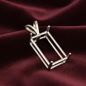 May include: A silver pendant setting with a rectangular frame and four prongs. The setting has a loop at the top for a chain and is designed to hold a rectangular gemstone. The pendant is displayed on a burgundy velvet surface.