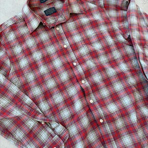 Puede incluir: Camisa abotonada a cuadros rojos, blancos y azules. La camisa tiene mangas largas y un cuello cl&aacute;sico. La etiqueta Pendleton es visible en el cuello. La camisa est&aacute; hecha de una tela suave y tejida.
