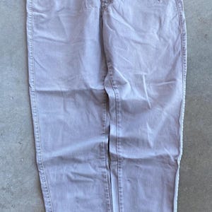 May include: Light grey denim trousers. These trousers feature a classic five-pocket design, a button and zip fastening, and belt loops. The fabric appears to be a medium-weight denim, suitable for casual wear. The trousers are laid flat on a concrete surface.