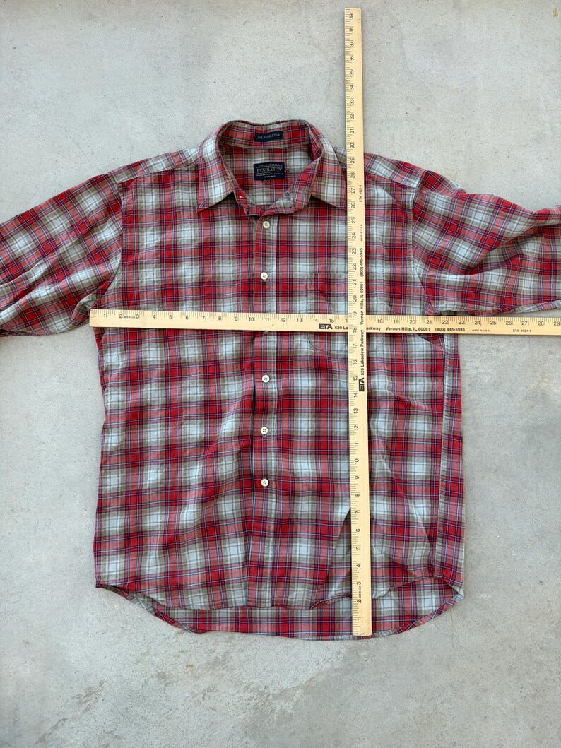 Puede incluir: Camisa a cuadros roja y gris con mangas largas. La camisa tiene un cuello cl&aacute;sico y se mide con una regla de madera. La longitud de la camisa es de aproximadamente 76 cm.