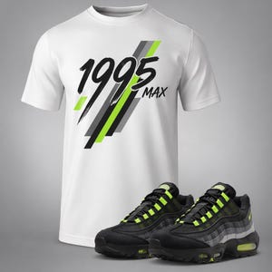 Puede incluir: Camiseta blanca con el texto "1995 MAX" en negro, gris y verde ne&oacute;n. Zapatillas deportivas negras y verde ne&oacute;n se muestran delante de la camiseta. Las zapatillas tienen un dise&ntilde;o de malla.