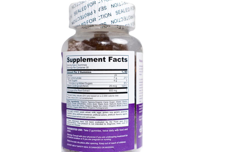 May include: A clear plastic bottle of gummies with a white label and purple accents. The label displays "Supplement Facts" and ingredient information. The bottle is sealed with a white cap that reads "SEALED FOR PROTECTION".