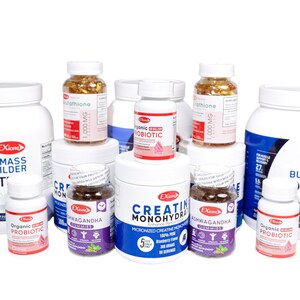 May include: A selection of white supplement bottles and jars with blue and red labels. Products include Mass Builder protein powder, Creatine Monohydrate, and Organic Probiotic. Some bottles contain capsules or gummies.