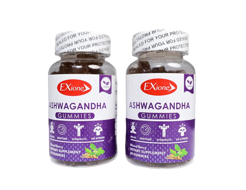 May include: Two clear plastic bottles of Exione Ashwagandha Gummies. Each bottle has a white label with purple accents and the words "Ashwagandha Gummies" in large text. The bottles are filled with dark brown gummies and sealed with a white cap.