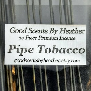 May include: A package of 20 premium incense sticks in the scent "Pipe Tobacco" from Good Scents By Heather. The sticks are silver and black and are packaged in a clear plastic bag with a white label.