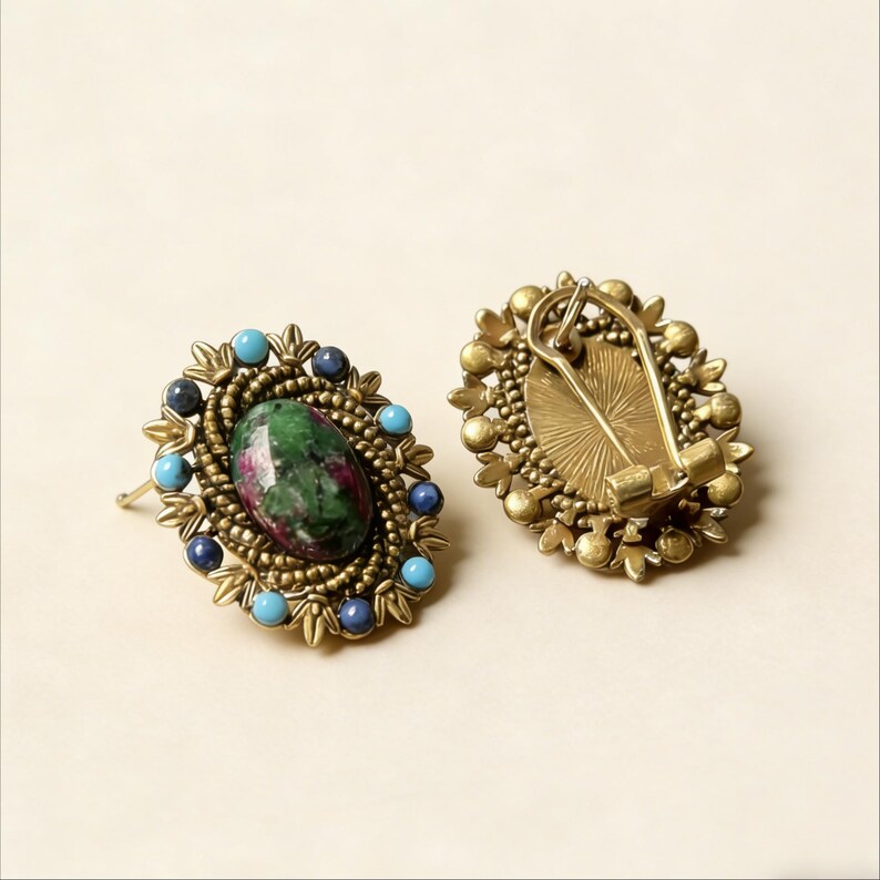 Peut inclure: Une paire de boucles d'oreilles de style vintage. Chaque boucle d'oreille pr&eacute;sente un centre ovale en pierre verte et rouge, entour&eacute; de perles turquoise et bleu marine. Les boucles d'oreilles ont un cadre en m&eacute;tal dor&eacute; avec une fermeture &agrave; clip.
