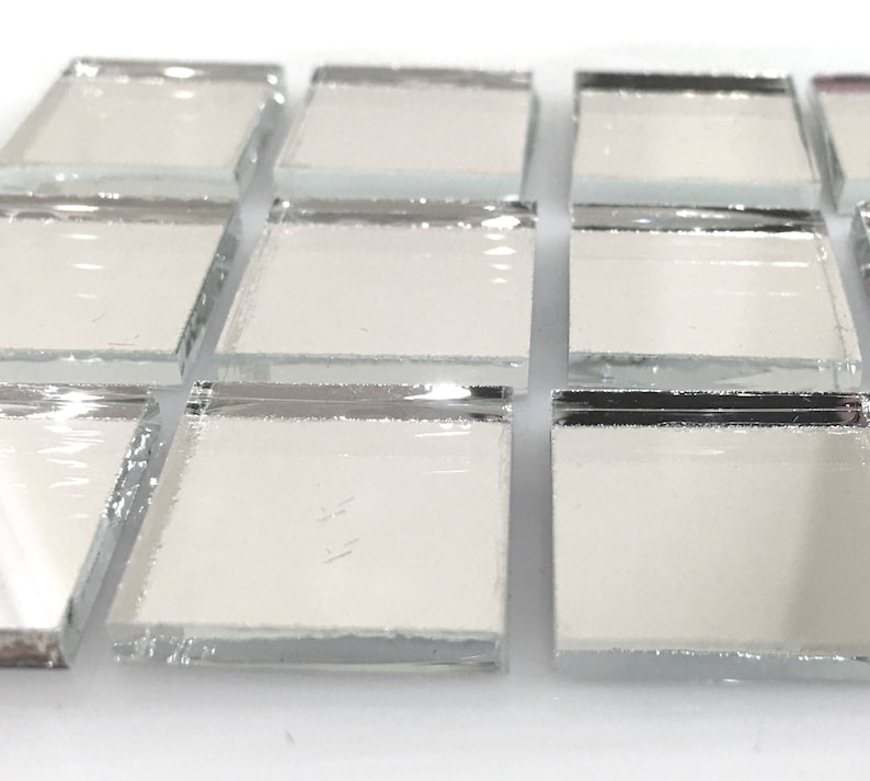 May include: A close-up of a sheet of small, square, silver-backed mirror tiles. The tiles are arranged in rows and columns, and the edges of the tiles are visible.