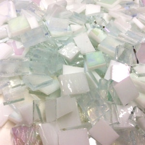 May include: A pile of white and iridescent glass mosaic tiles. The tiles are various sizes and shapes, with some having a slightly frosted finish.