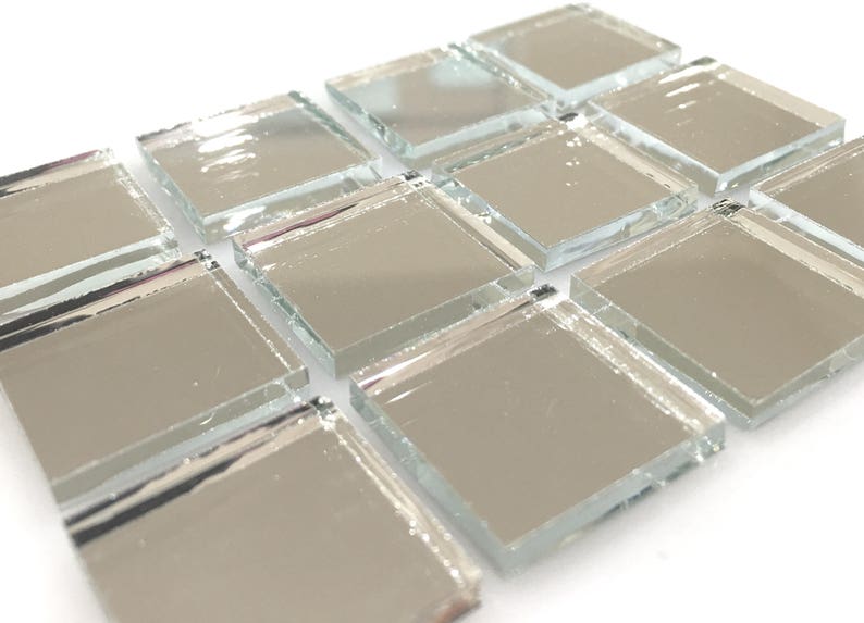 May include: Silver mirrored glass tiles arranged in a staggered pattern. The tiles are square and have a reflective surface.
