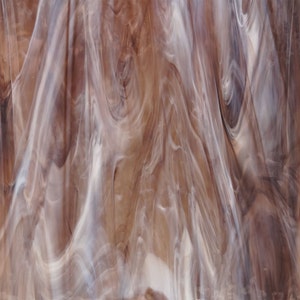 May include: Abstract brown and white swirled glass with a translucent, marbled effect.
