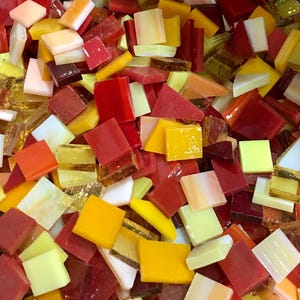 May include: A collection of small, square glass tiles in shades of red, orange, yellow, and white. The tiles are perfect for mosaic projects.