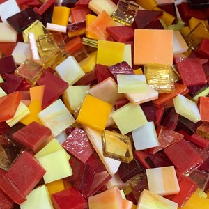 May include: A variety of small, square glass tiles in shades of red, orange, yellow, and white. The tiles are perfect for mosaic projects.