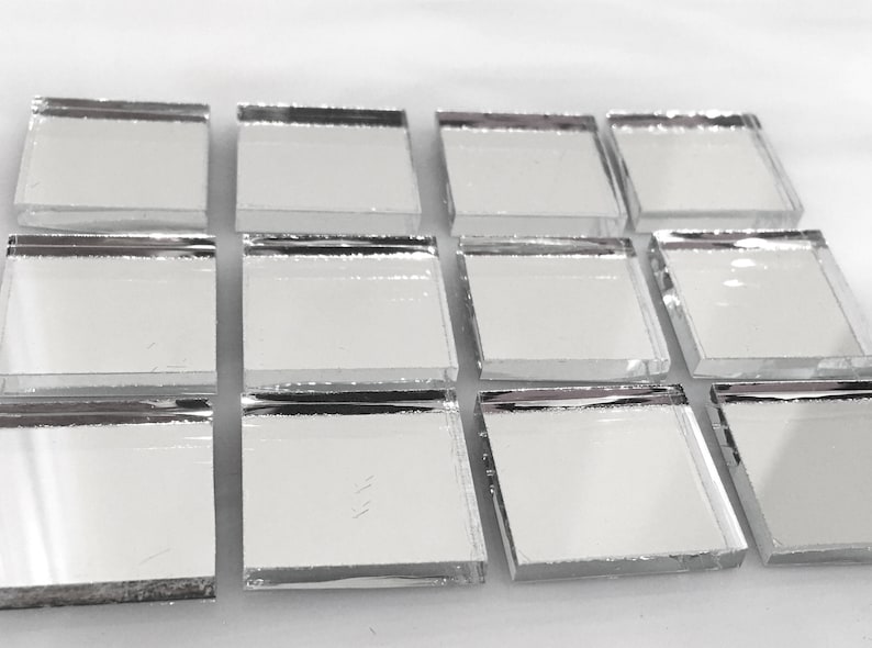 May include: Ten square silver mirror tiles with beveled edges. The tiles are arranged in three rows, with three tiles in the top row, three in the middle row, and four in the bottom row.