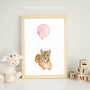 May include: A watercolor illustration of a tiger cub holding a pink balloon. The illustration is framed and displayed on a white surface with a stuffed sheep and wooden blocks spelling "FAMILY".