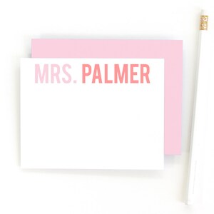 May include: A white card with a pink border and the text "MRS. PALMER" in pink and red lettering.